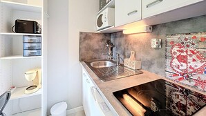 Una cocina moderna con armarios blancos, un lavamanos de acero inoxidable y un horno empotrado.