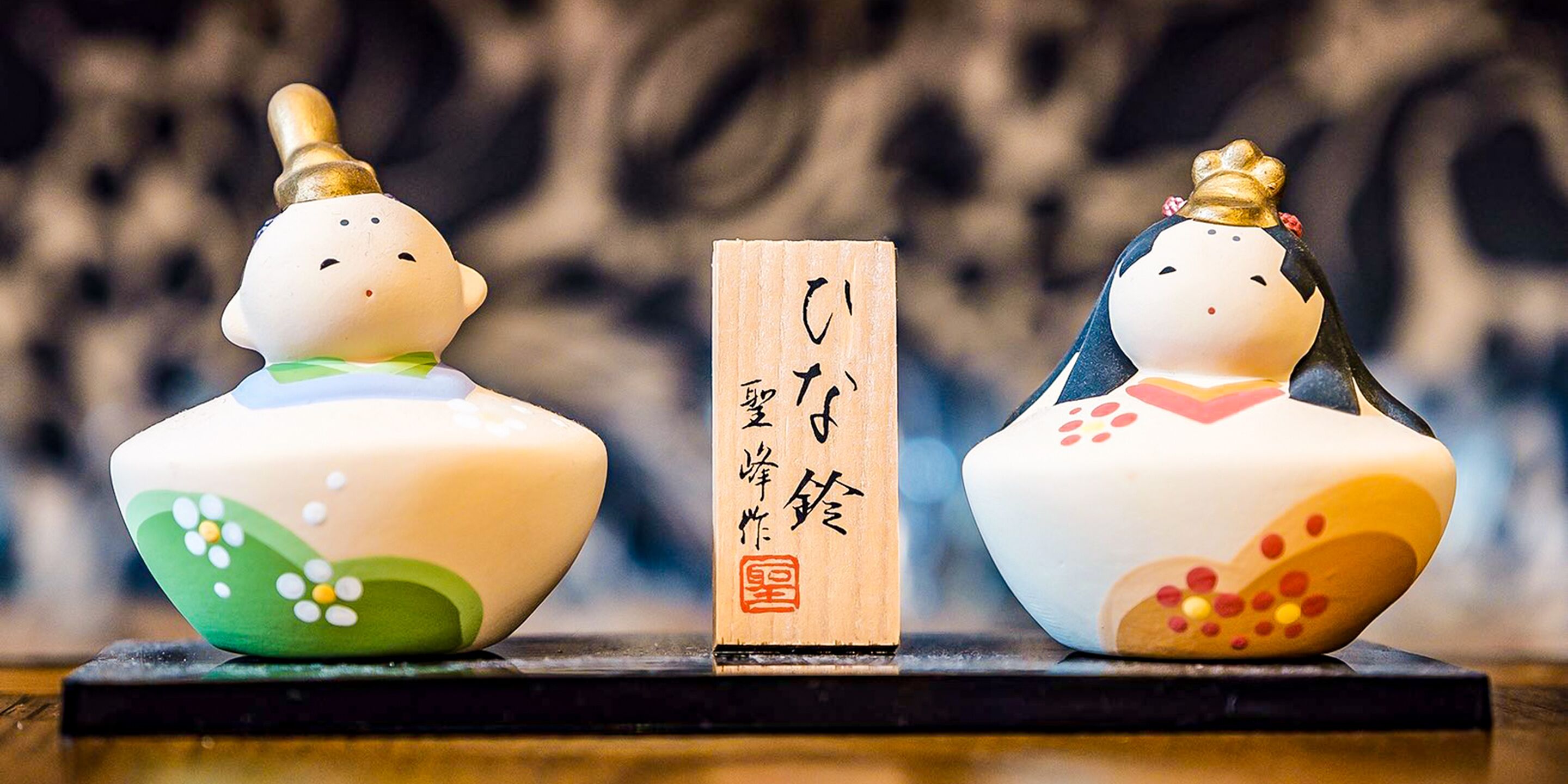 Two ceramic figurines with inscriptions on a wooden block.