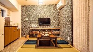 A compact room with a kitchenette, a television mounted on the wall, a small table with tea set, and tatami mats on the floor. - Shirakawa Seiryuan (Kyoto)