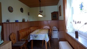 Zona pranzo con una panca in legno, un tavolo con tovaglia floreale e un lampadario.