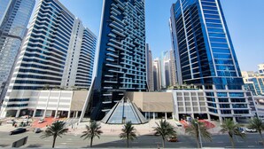 A modern urban area with high-rise buildings, palm trees, and a clear sky. - HiGuests - DAMAC Maison Prive Tower A (Dubai)