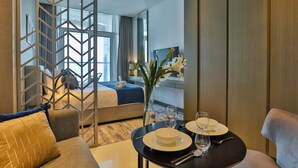 A hotel room with a bed, a dining table set with plates, glasses, and a vase of flowers. - HiGuests - DAMAC Maison Prive Tower A (Dubai)