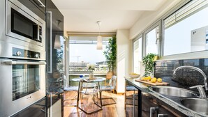 A modern kitchen with a built-in oven, stainless steel sink, and a dining area with a round table and chairs.
