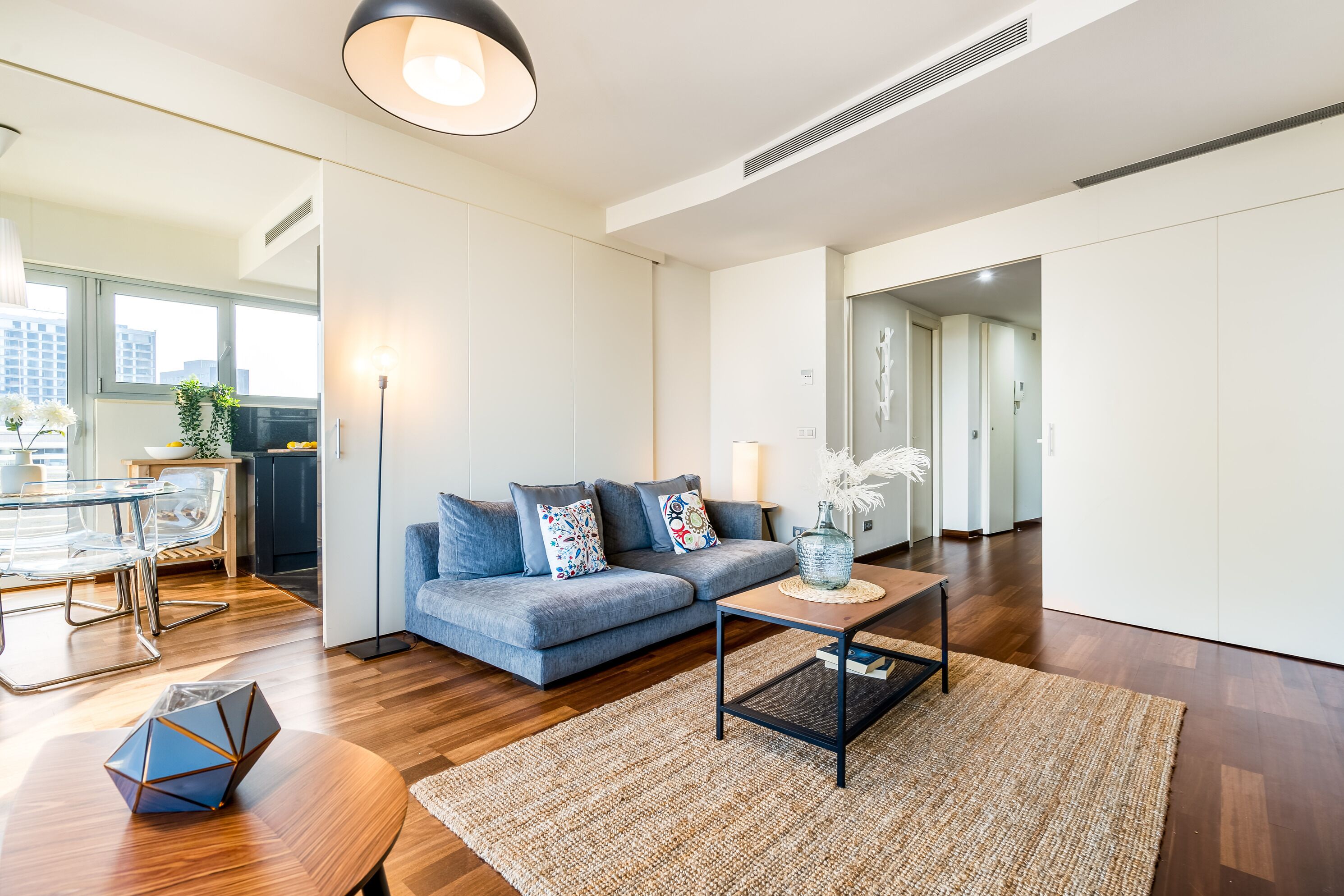 Un salon moderne comprenant un canapé, une table basse et un coin repas avec une table et des chaises en verre.