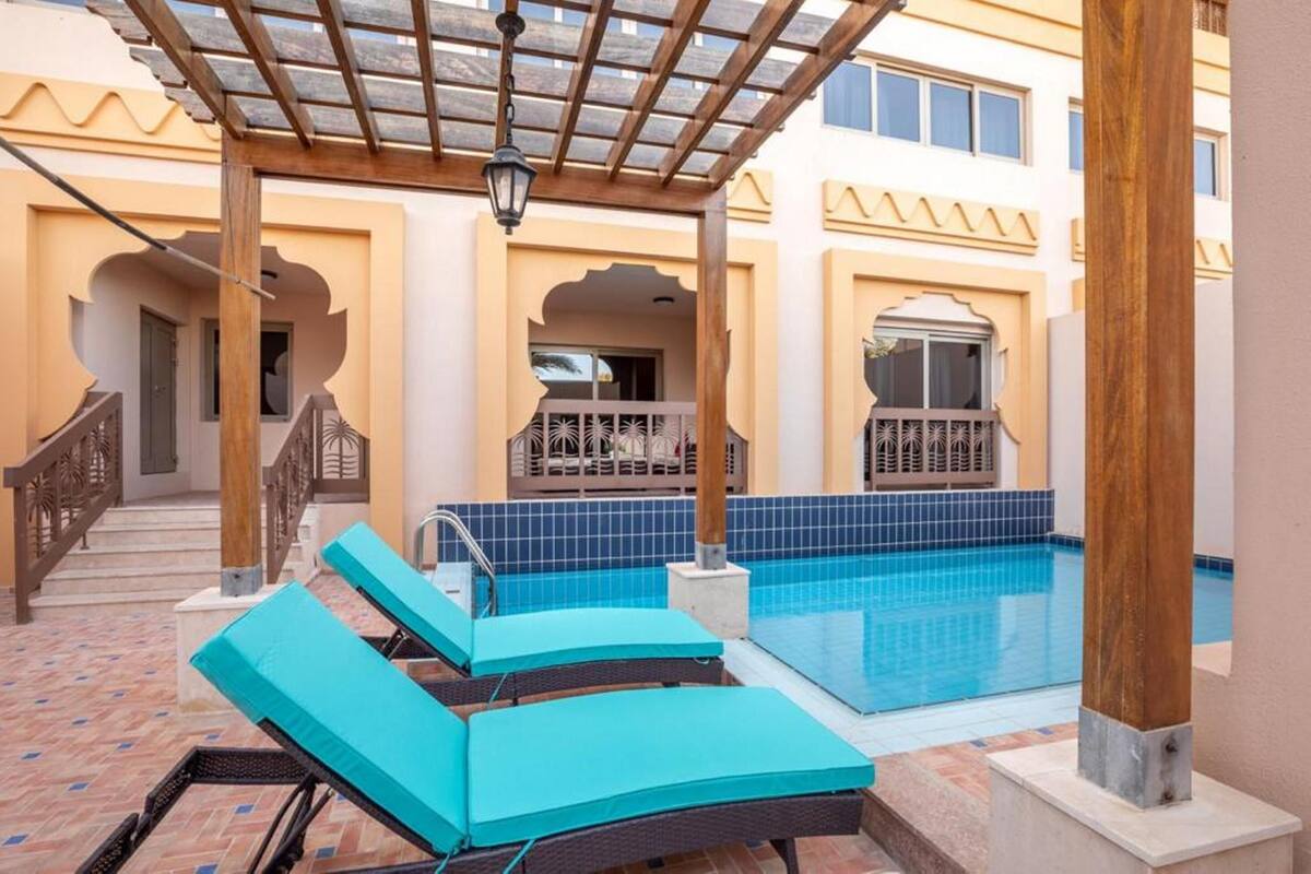A pool area with lounge chairs and a pergola.