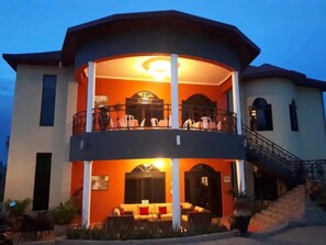 A two-story building with a balcony on the upper floor, a staircase leading to the entrance, and a well-lit entrance area.