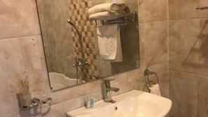 A bathroom with a sink, mirror, and towel rack. - Puma Garden and Suites (Kigali)
