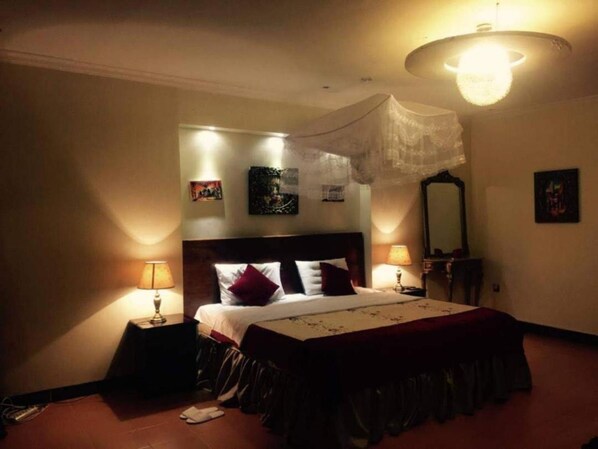 A bedroom with a bed, bedside lamps, a mirror, and wall art.