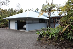 A single-story building with a garage, surrounded by dense vegetation.