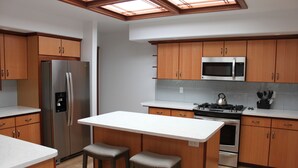 Une cuisine moderne avec des meubles en bois, des appareils électroménagers en acier inoxydable et un îlot central doté de tabourets.