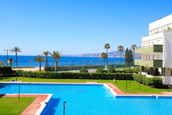 Une piscine offrant une vue dégagée sur la mer et un bâtiment moderne doté de balcons.
