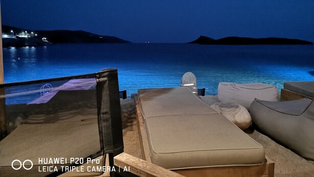 A lounge area with a view of the sea and distant hills, featuring a Huawei P20 Pro and a Leica Triple Camera.