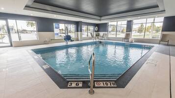 A large indoor swimming pool with clear water, surrounded by a tiled floor and walls.