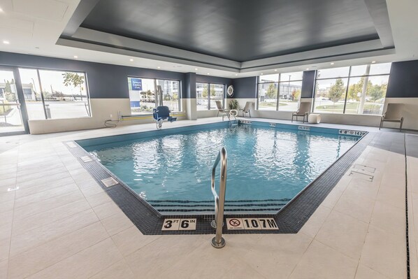 A large indoor swimming pool with clear water, surrounded by a tiled floor and walls. - Holiday Inn Express & Suites Toronto Airport South by IHG (Toronto)