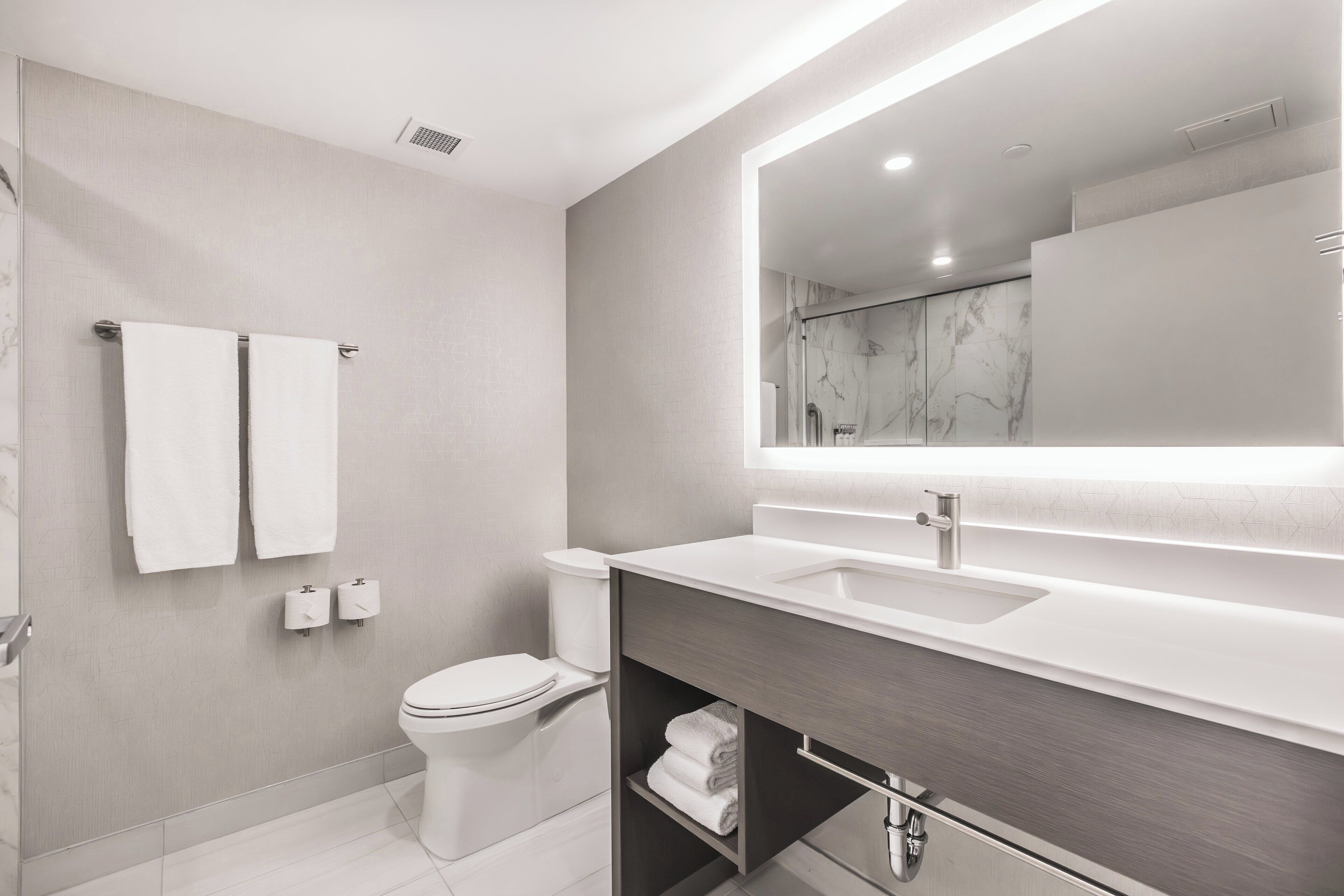 A modern bathroom with a toilet, sink, and mirror.