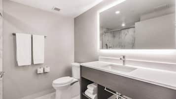 Un baño moderno con inodoro, lavamanos y espejo.