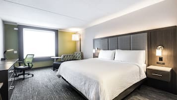Een hotelkamer met een groot bed, een bureau, een stoel en een raam.