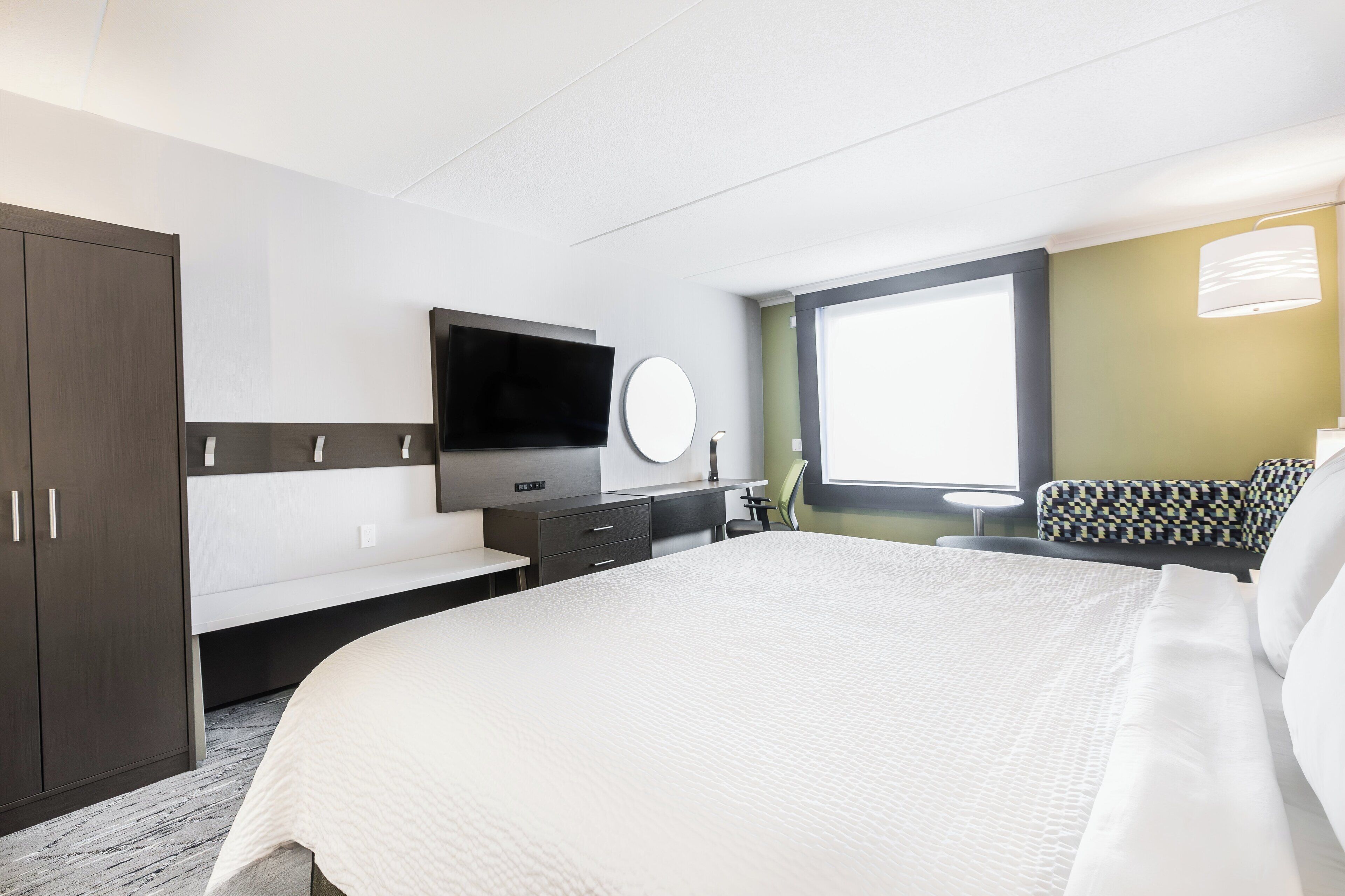 Une chambre d’hôtel avec un grand lit, une télévision, un bureau et une fenêtre.