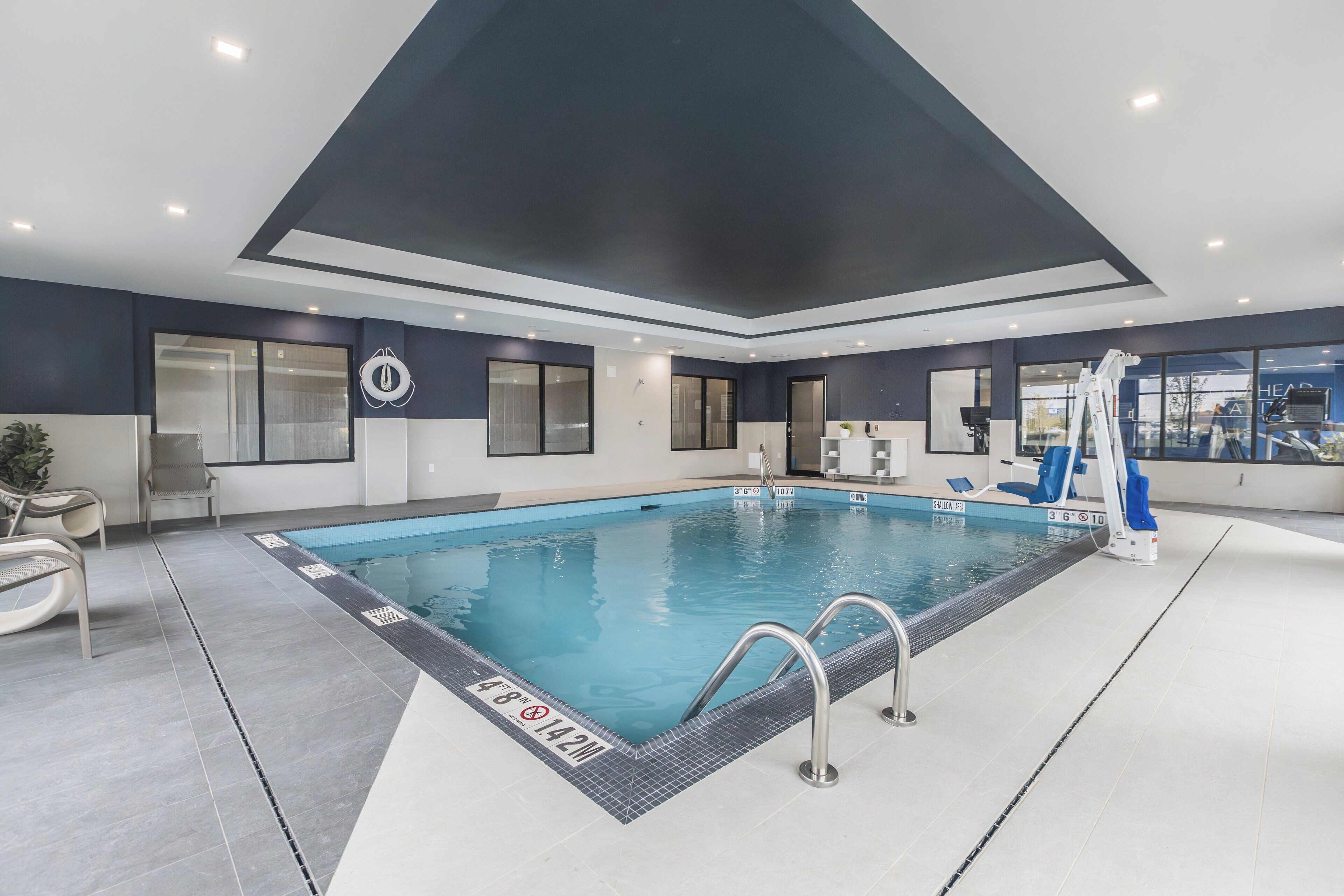 Una piscina interior con agua cristalina, rodeada de paredes y suelo azulejados.