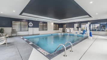 Una piscina interior con agua cristalina, rodeada de paredes y suelo azulejados.