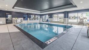 An indoor swimming pool with clear water, surrounded by a tiled floor and walls, and a ceiling with recessed lighting. - Holiday Inn Express & Suites Toronto Airport South by IHG (Toronto)