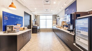 A modern kitchen with a breakfast bar, a yogurt and egg station, and a large window providing natural light. - Holiday Inn Express & Suites Toronto Airport South by IHG (Toronto)