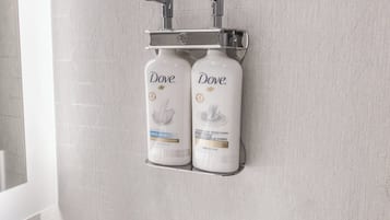 A bathroom with two Dove hand wash bottles mounted on a wall-mounted holder.