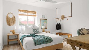 A bedroom with a bed, bedside tables, a hanging chair, a wooden bench, a window with blinds, and a ceiling fan. - 4 bedroom private home in Coronado Historic District by PHX Stays (Phoenix)