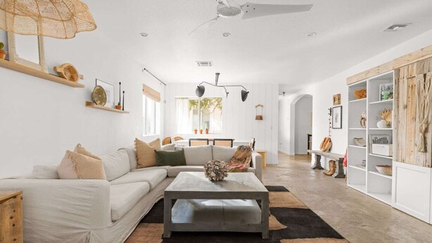 A spacious living room with a white sofa, a coffee table, and a bookshelf. - 4 bedroom private home in Coronado Historic District by PHX Stays (Phoenix)
