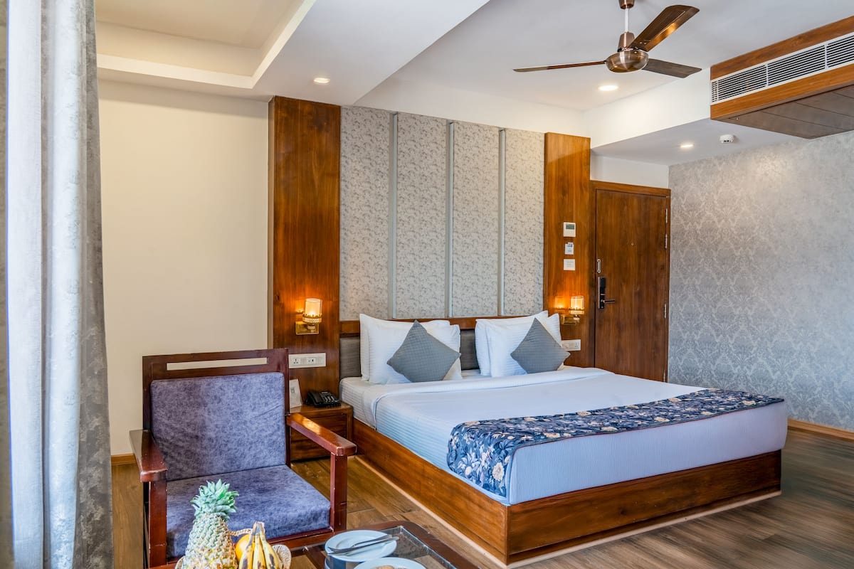A bedroom with a wooden bed, a nightstand, a chair, and a small table with fruits.