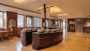 A spacious hotel lobby with a central buffet area, wooden paneling, large windows, and a chandelier. - Paandora Grand Udaipur (Udaipur)