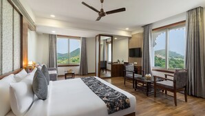 A hotel room with a large bed, a desk, a chair, and a TV. - Paandora Grand Udaipur (Udaipur)