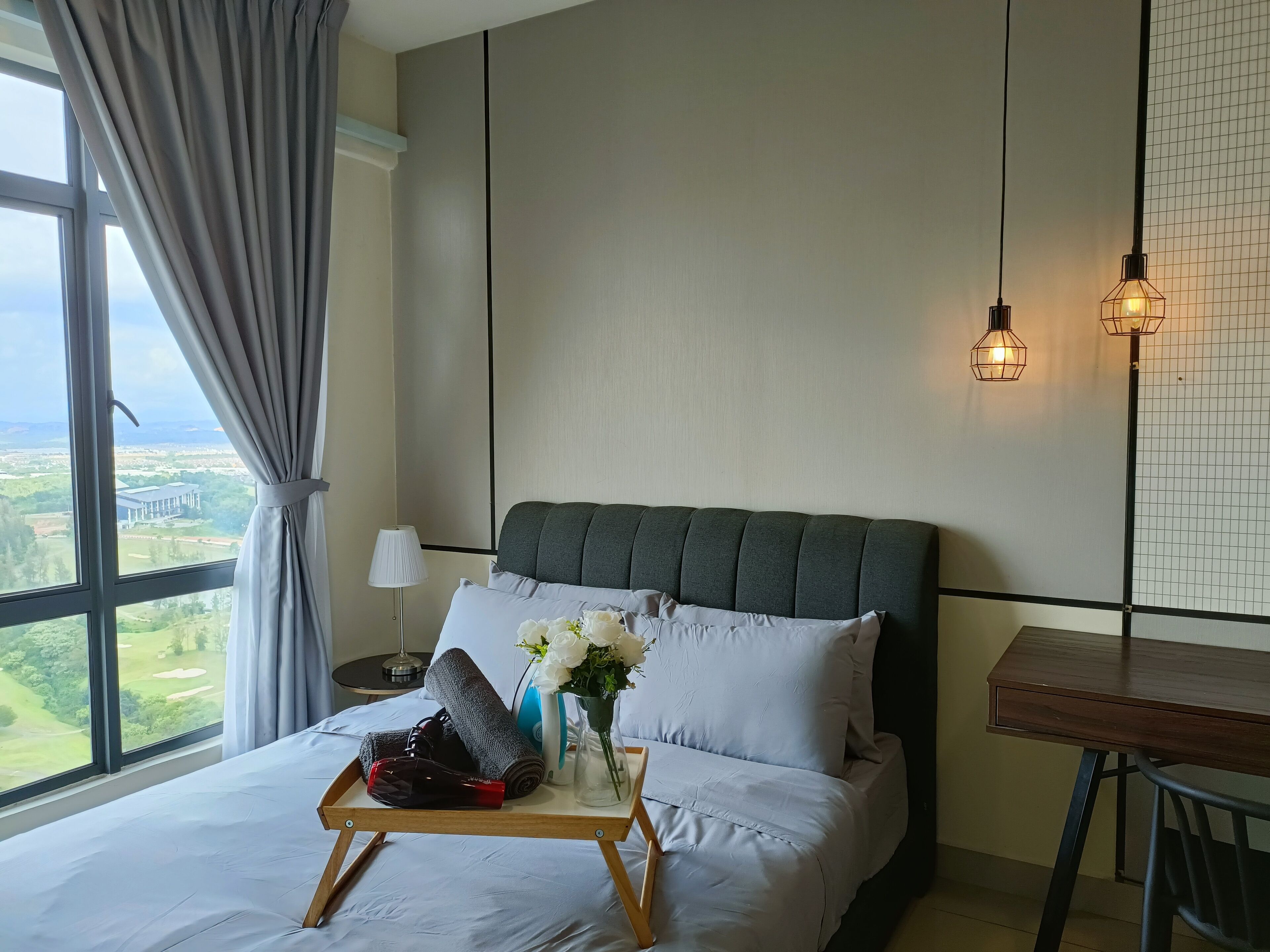 A hotel room with a large bed, a bedside table, a desk, and a view of a golf course.
