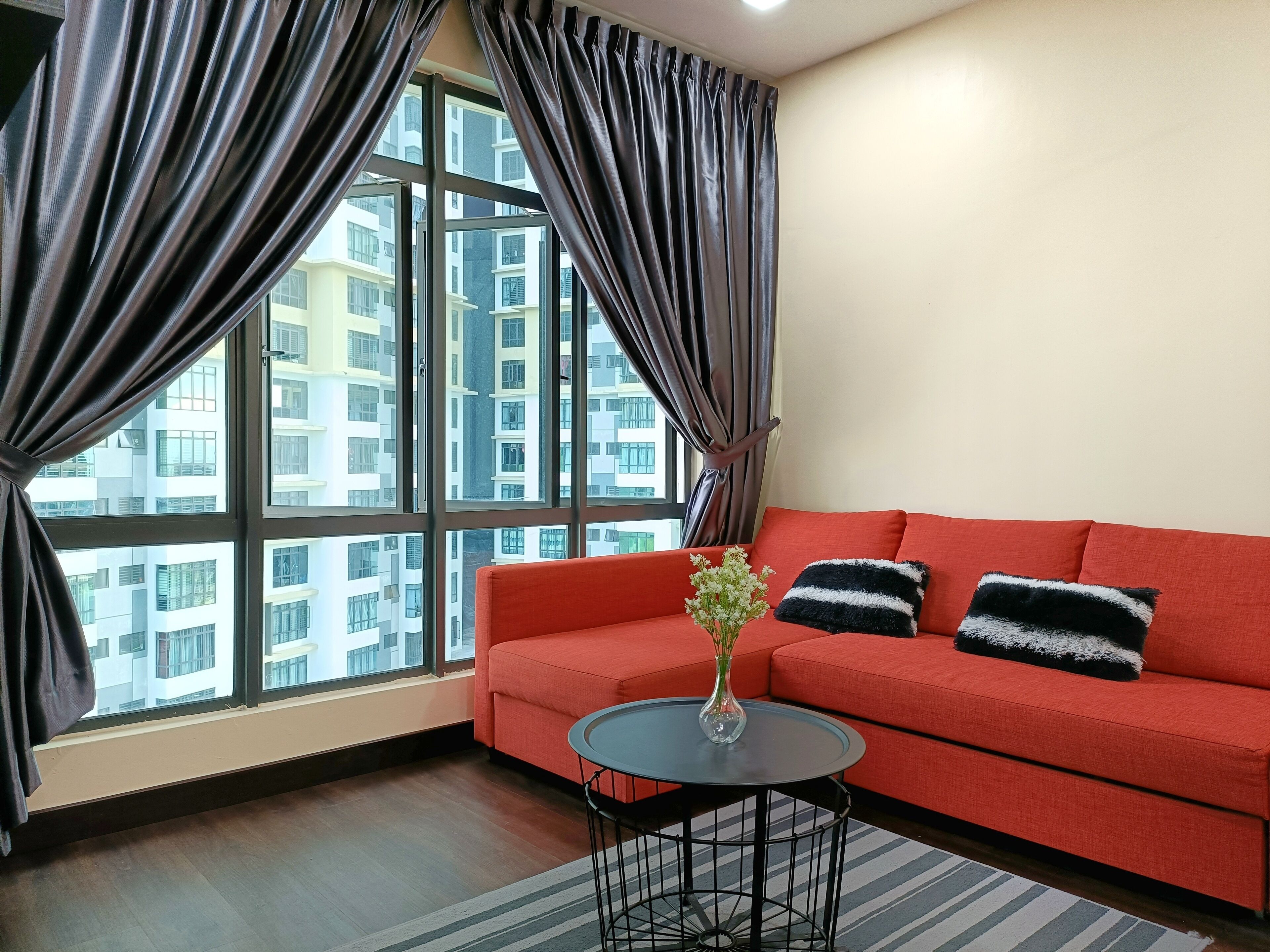 A modern living room with a red sofa, a round black table, and a vase with flowers.