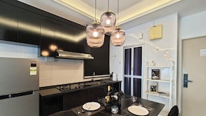 Cocina moderna con muebles negros, campana extractora de acero inoxidable y comedor con una mesa para dos.