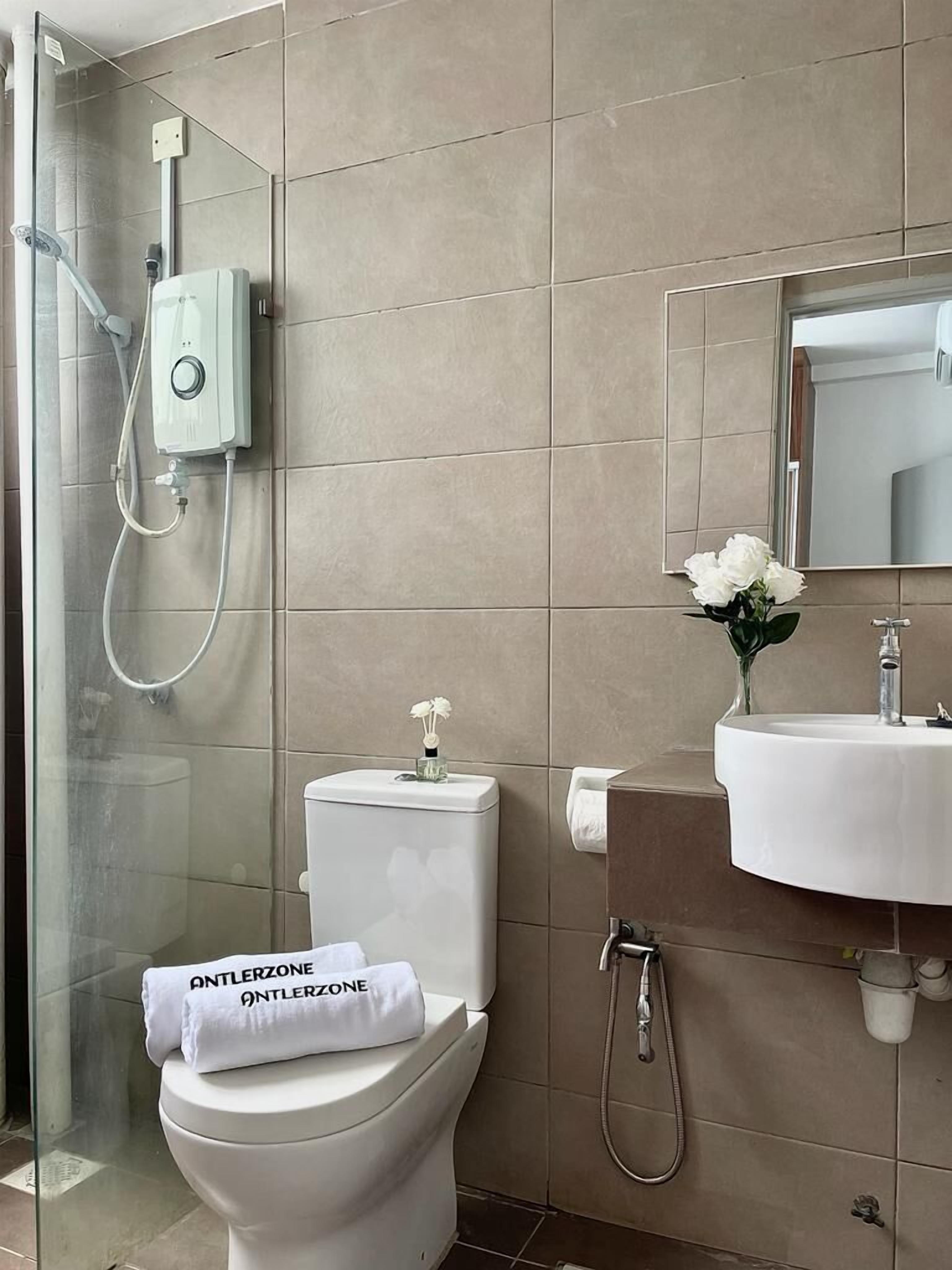 Une salle de bain moderne avec une douche à parois de verre, des toilettes avec un porte-serviette, un lavabo et un miroir.