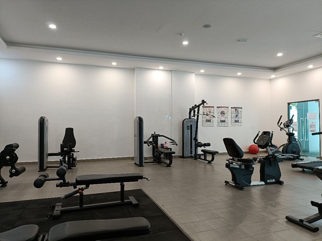 Uma academia com diversos equipamentos de exercício, incluindo esteiras, aparelhos de musculação e pesos livres.