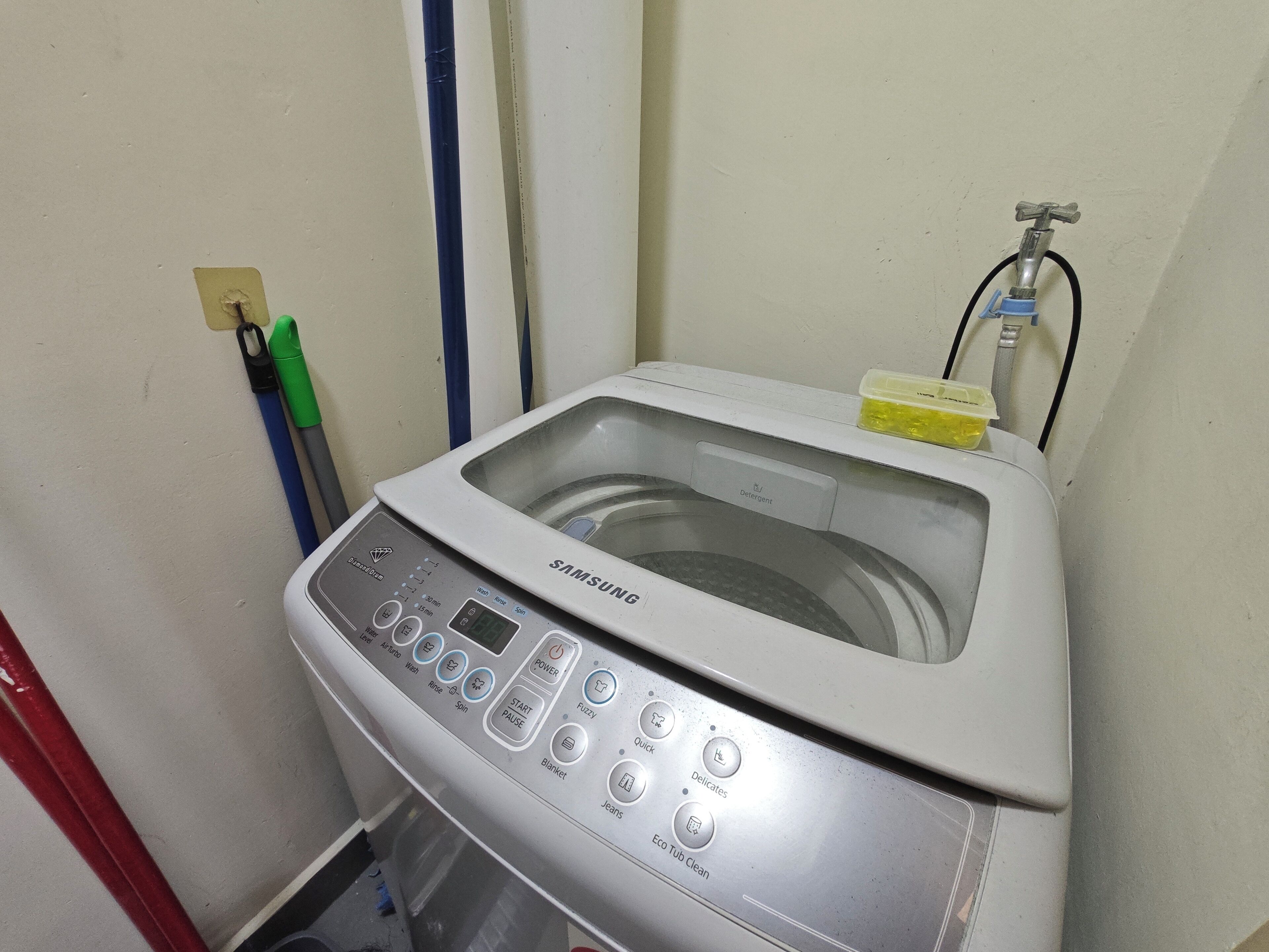 A Samsung washing machine with a transparent water tank, control panel, and a detergent compartment.