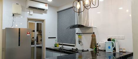 A modern kitchen with a stainless steel refrigerator, a built-in oven, a gas stove, and a black marble countertop.