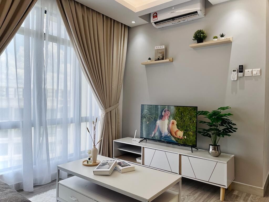A modern living room with a flat-screen TV, a white console table, and a large window with sheer curtains.