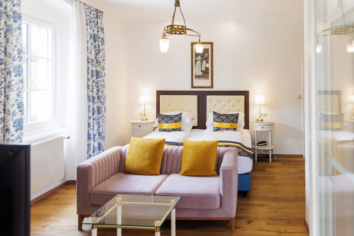 Un dormitorio con cama, dos mesitas de noche, un sofá y una mesa de centro de vidrio.