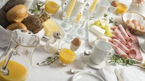 Un plateau de petit-déjeuner avec du pain, des œufs, du fromage, du jambon et du jus de fruits.