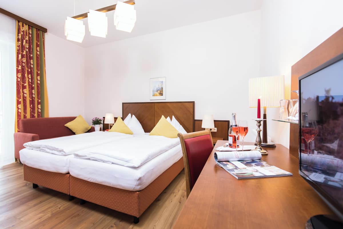 Una habitación de hotel con cama, escritorio, televisor y ventana.