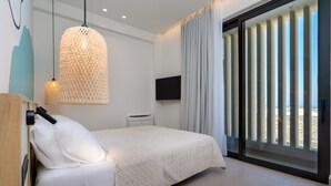 Une chambre moderne avec un grand lit, un luminaire suspendu, un téléviseur à écran plat et une porte-fenêtre coulissante donnant sur l’extérieur.