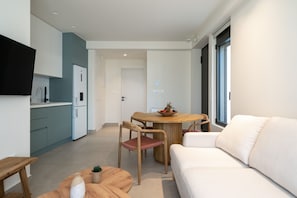 A modern kitchen with teal cabinets, a wooden dining table, and a white sofa. - KoNoSo Luxury Apartments (Heraklion)