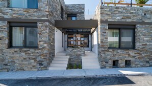 Un bâtiment moderne avec une façade en pierre, de grandes fenêtres et une entrée abritée.