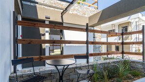 Une terrasse extérieure avec un banc en pierre, une table et deux chaises.