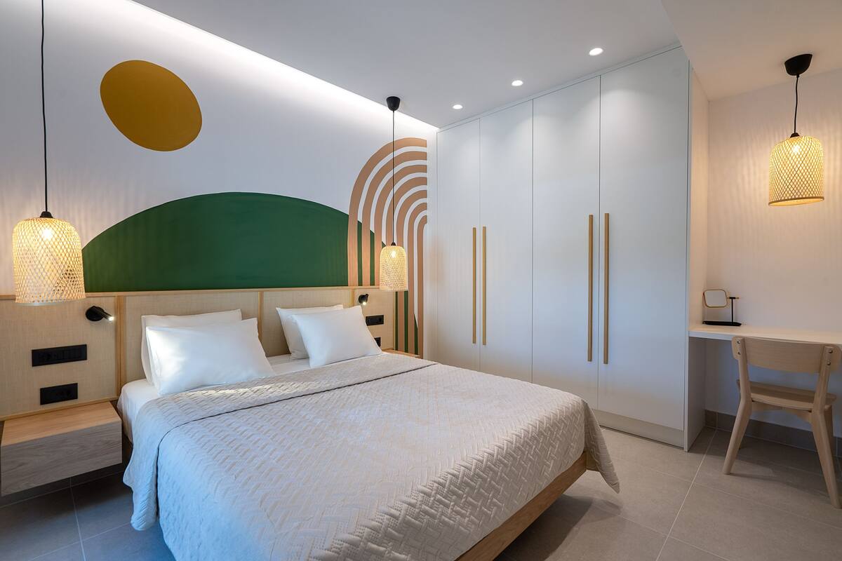 A modern bedroom with a bed, bedside tables, a desk, and a wardrobe.