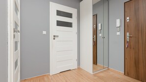 A hallway with a white door, a wooden door, and a mirror reflecting the door.