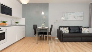 A modern kitchen with white cabinets, a black microwave, and a dining area with a table and chairs.